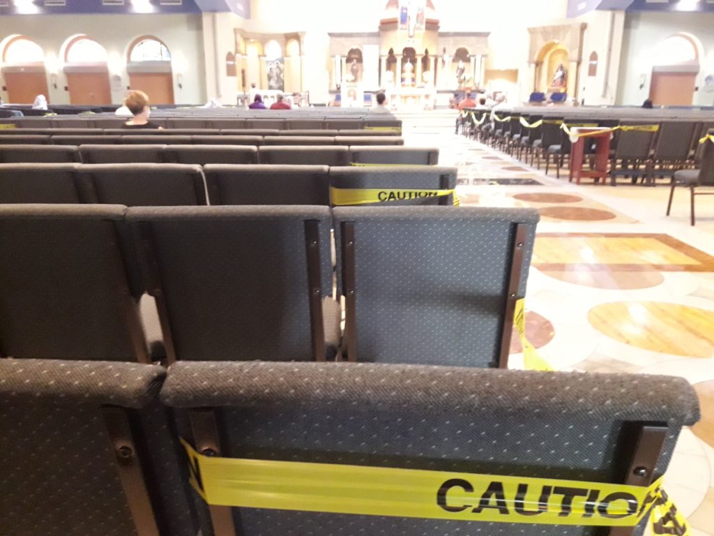 The seats with yellow -caution tape designates the rows allowed for use. St. Claire of Assisi, Surprise, Arizona, USA. Photo by Jorge Mission